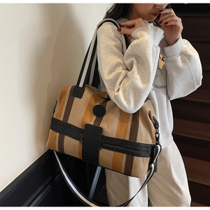 Detail of striped travel bag with woven handles and silver metallic hardware accents