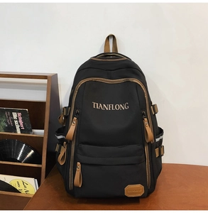 Close-up of black backpack featuring brown leather trim and metal buckles with TIANFLONG branding