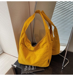 Detail of ginger yellow canvas tote bag featuring wrinkled texture and front pocket design