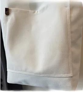 Detail of canvas tote bag showing cream fabric texture and leather metal buckle detail
