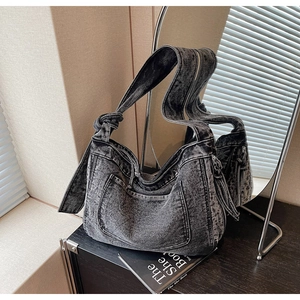 Detailed close-up of retro washed denim hobo bag featuring knot strap and pocket design
