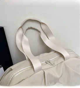 Detailed close-up of a cream travel bag featuring reinforced handles and a smooth metal zipper