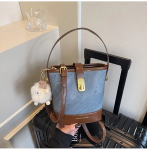 Détail du sac seau en denim et cuir avec fermoir doré et pendentif peluche blanche