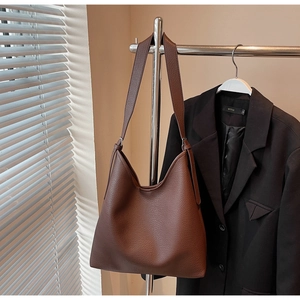 Detail of a brown lychee pattern leather hobo bag hanging on a metal rack