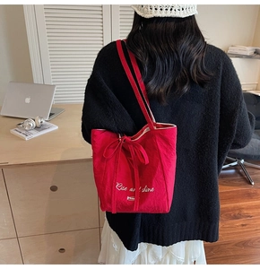 Detail of red canvas tote bag with bow decoration and Rise and Shine lettering print