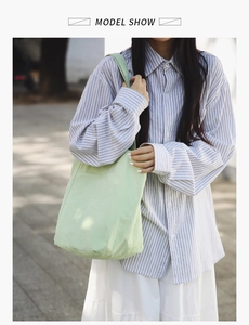 Detail of light green canvas tote bag with large front pocket and shoulder strap