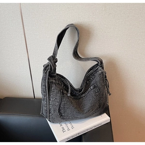 Detail of grey denim hobo bag with knotted strap and utility pocket in vintage style