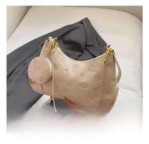 Detail of beige shoulder bag with bear embossing and a branded coin purse charm
