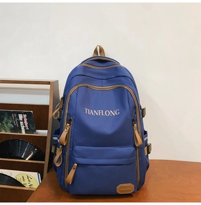 Detailed close-up of dark blue laptop backpack with brown zipper accents and pockets