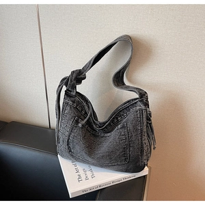 Detail of vintage washed denim tote bag with knot strap and side zipper pocket
