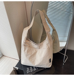 Close-up of cream pleated nylon tote bag texture with black logo on dark wood table