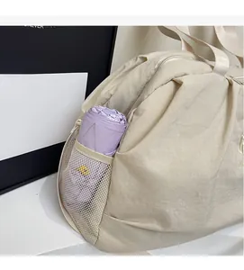 Close-up of beige travel bag side mesh pocket holding a purple folding umbrella