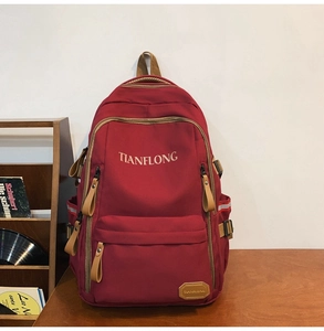 Macro shot of dark red backpack fabric with golden TIANFLONG logo and leather accents