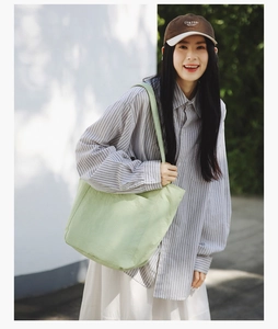 Close-up of mint green canvas tote bag featuring an outer pocket and soft fabric texture