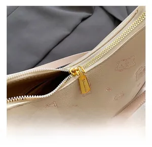 Detailed close-up of beige leather bag with gold hardware and animal embroidery
