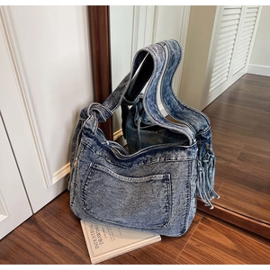 Close-up of vintage washed denim tote bag with side fringe and knotted shoulder strap