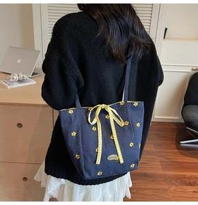 Detail of navy blue canvas bag featuring white flower embroidery and yellow bow accent