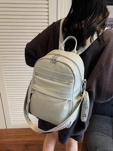 Mint green leather backpack with woven straps and small pouch in a cozy indoor setting