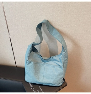 Detail view of water-washed nylon fabric and side logo label on the blue hobo bag