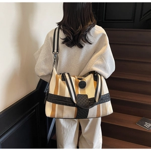 Detailed view of striped canvas travel tote bag with black leather trim and shoulder strap