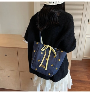 Detail of blue denim tote bag with yellow floral embroidery and a cute checkered bow