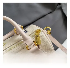 Macro detail of beige pebble leather handbag featuring floral embroidery and gold zipper