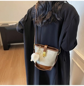 Détail du sac seau gris-vert avec garniture en cuir marron et breloque en peluche