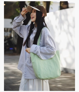 Detail of light green canvas tote bag with long straps during outdoor street style session