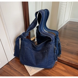 Detail of blue denim tote bag texture and large front pocket on wooden floor with mirror