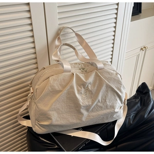 Detail of beige travel bag with NINGJIA embroidery, side mesh pocket and wide strap
