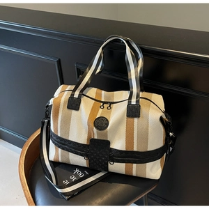 Detail of striped canvas travel bag with leather trim and wide adjustable shoulder strap