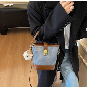 Détail du sac seau en jean et cuir marron avec charm mouton et boucle métallique dorée