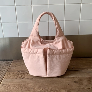 Vue détaillée du sac seau rose en nylon avec design multi-poches et texture textile