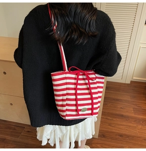 Close-up of red and white striped canvas tote bag with ribbon bow and metal handmade tag