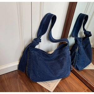 Close-up of deep blue denim tote bag featuring white contrast stitching and side zipper