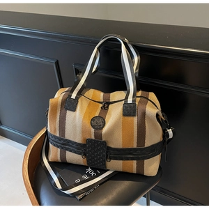 Close-up of striped travel bag with woven texture and leather details on a dark chair