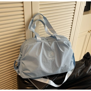 Detail of light blue travel bag showing waterproof nylon texture and side mesh pocket