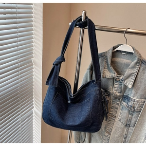 Detail of vintage denim tote bag showing knotted shoulder strap and fringe zipper