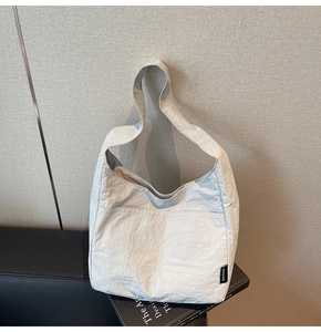 Detailed view of white minimalist tote bag featuring unique crinkled fabric texture and brand label