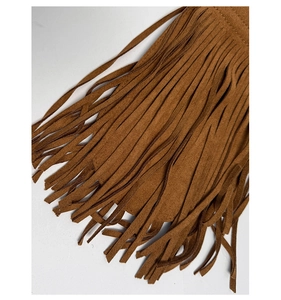 Gros plan des franges en daim marron sur le sac seau minimaliste en bandoulière