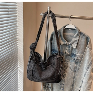 Detail of grey washed denim hobo bag with large front pocket and knotted shoulder strap
