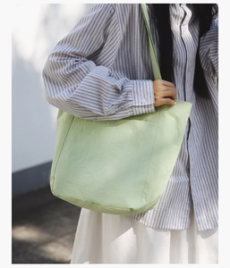 Detail shot of a mint green minimalist tote bag with soft fabric texture on a model
