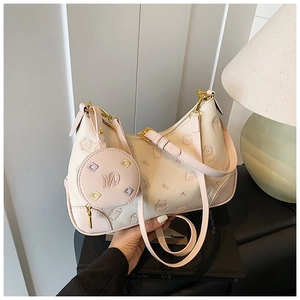 Detail showing beige litchi leather dumpling bag with pink edges and gold-tone metal M logo
