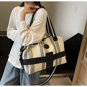 Detail of striped canvas travel bag with top handles and adjustable shoulder strap