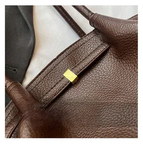 Detailed macro view of dark brown litchi grain leather texture and golden metal buckle