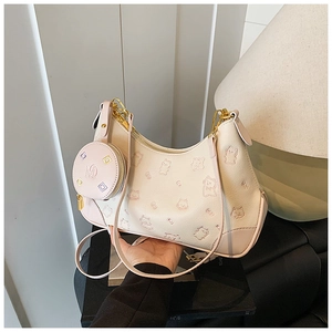 Close-up of cream textured leather bag with embossed cat patterns and mini round pouch