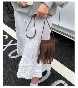 Détail du sac bandoulière en cuir marron foncé avec de longues franges au style bohème