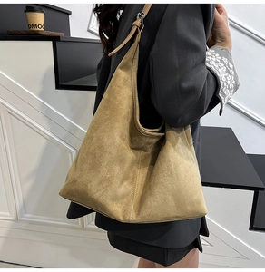 Detail of adjustable metal buckle and stitching on khaki suede shoulder tote bag