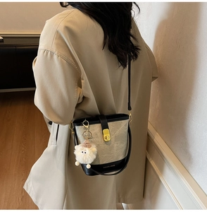 Détail du sac seau contrasté avec finitions dorées et charmant mouton en peluche blanc