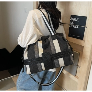 Close-up of large striped travel tote with detachable shoulder strap and round logo